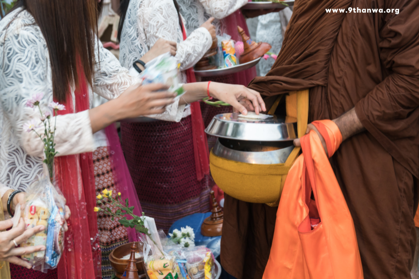 Devotees offering food to monks at a Thai temple as part of a spiritual ritual to gain merit